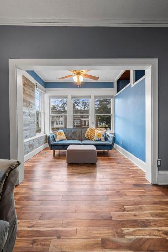 The sunroom showcases a statement wood-paneled accent wall and is filled with natural light.