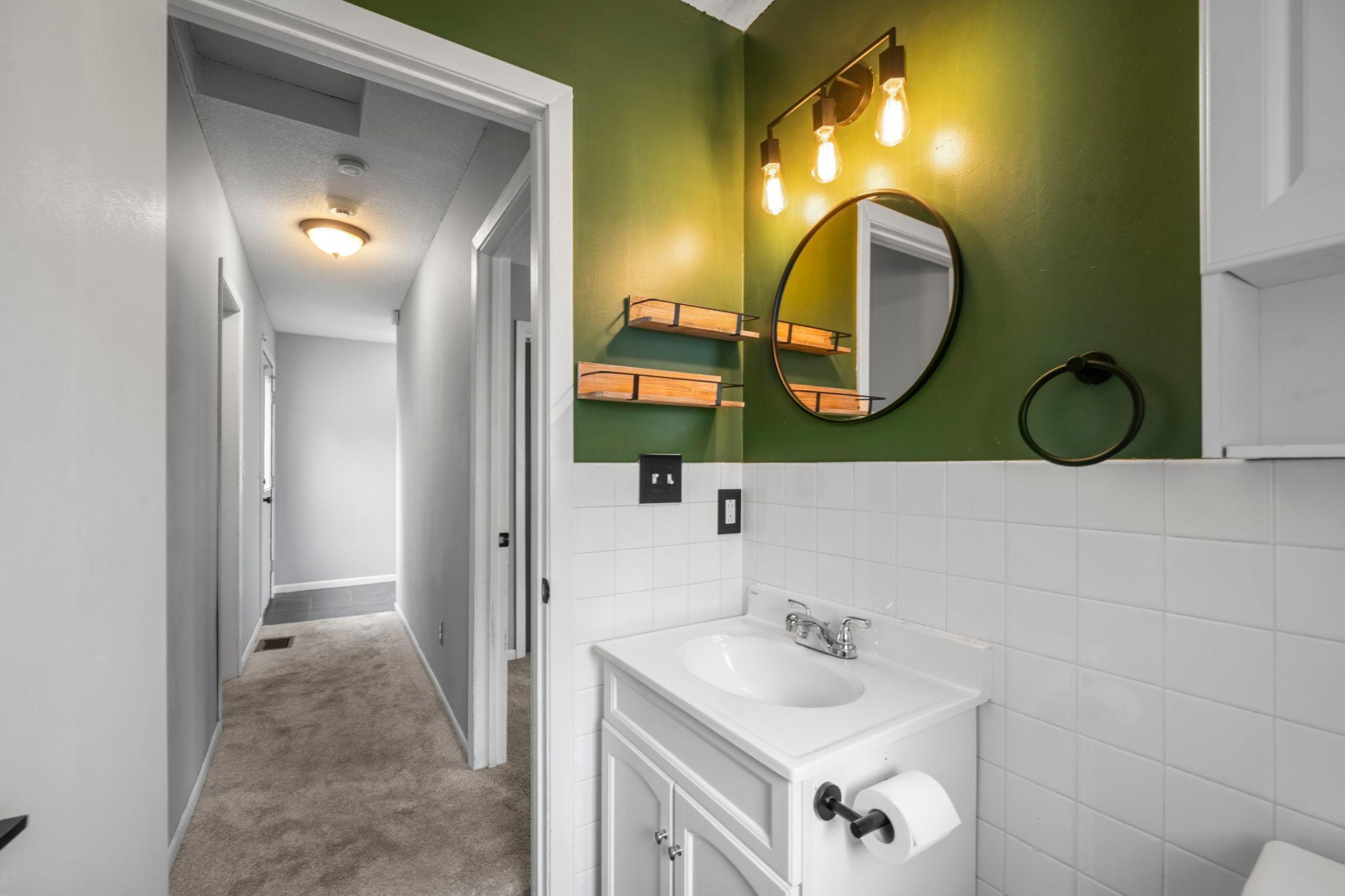 A convenient half bathroom, located just outside bedroom two, features tile flooring and a single vanity.