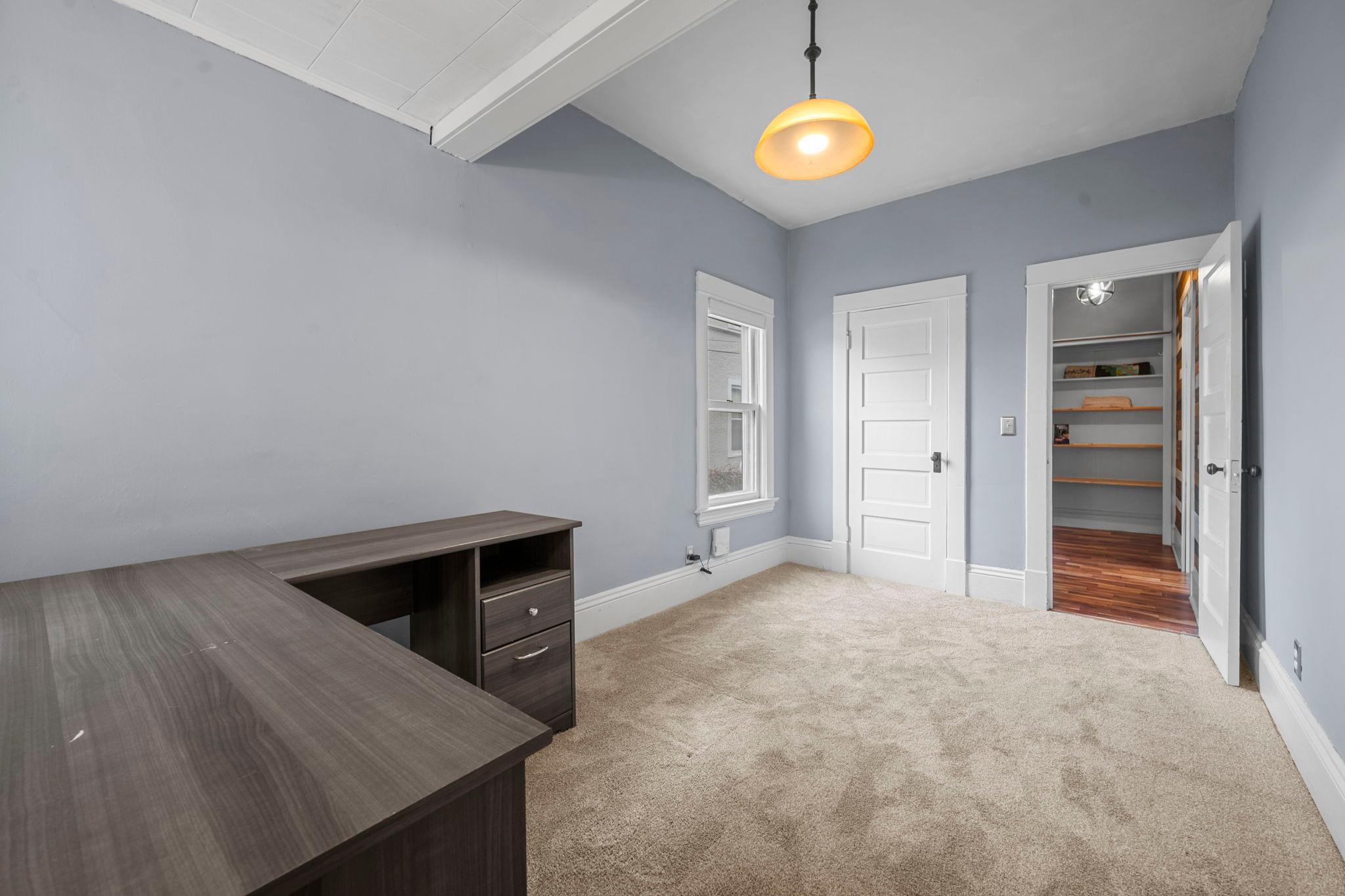 Bedroom one, located just off the dining room, features carpeting, a hanging light fixture, ample closet space, and convenient access to a full bathroom just steps away.