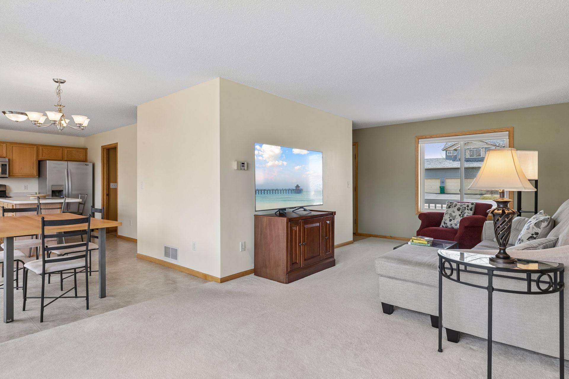 Living room features large new windows and a nearby dining room patio door allowing in natural light on both sides and a nice view of the nearly 1/2 acre lot. View into dining room and spacious kitchen with an island and stainless steel appliances