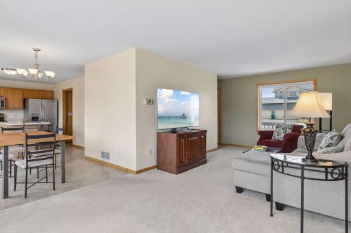Living room features large new windows and a nearby dining room patio door allowing in natural light on both sides and a nice view of the nearly 1/2 acre lot. View into dining room and spacious kitchen with an island and stainless steel appliances