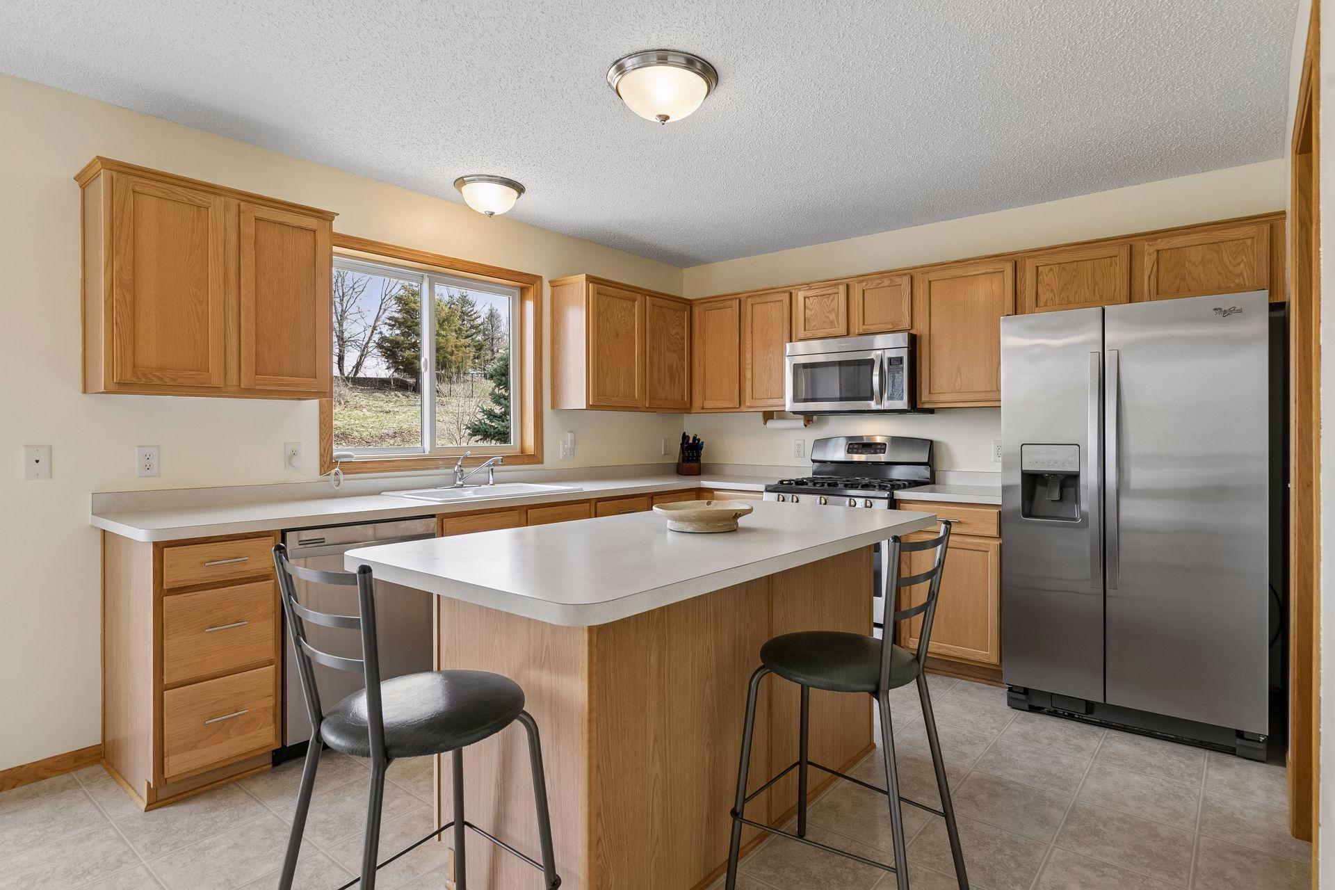 49 Windsor Wood Path - Spacious kitchen with plenty of cabinetry and countertop space and newer stainless steel appliances. Breakfast bar / homework seating area right in the kitchen with nice views of the backyard.