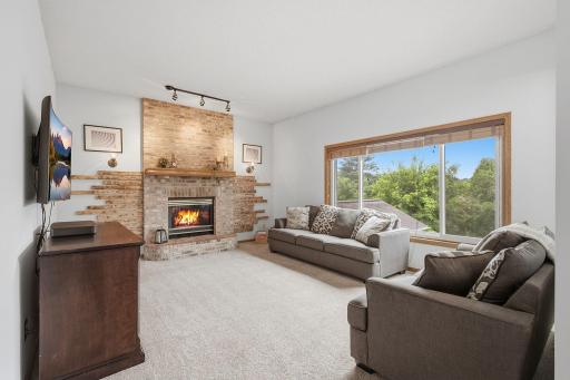 Comfortable main-level family room featuring a brick gas fireplace and large picture window