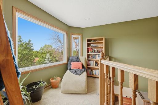 Upper-level reading loft / sitting room with large window and peaceful backyard views