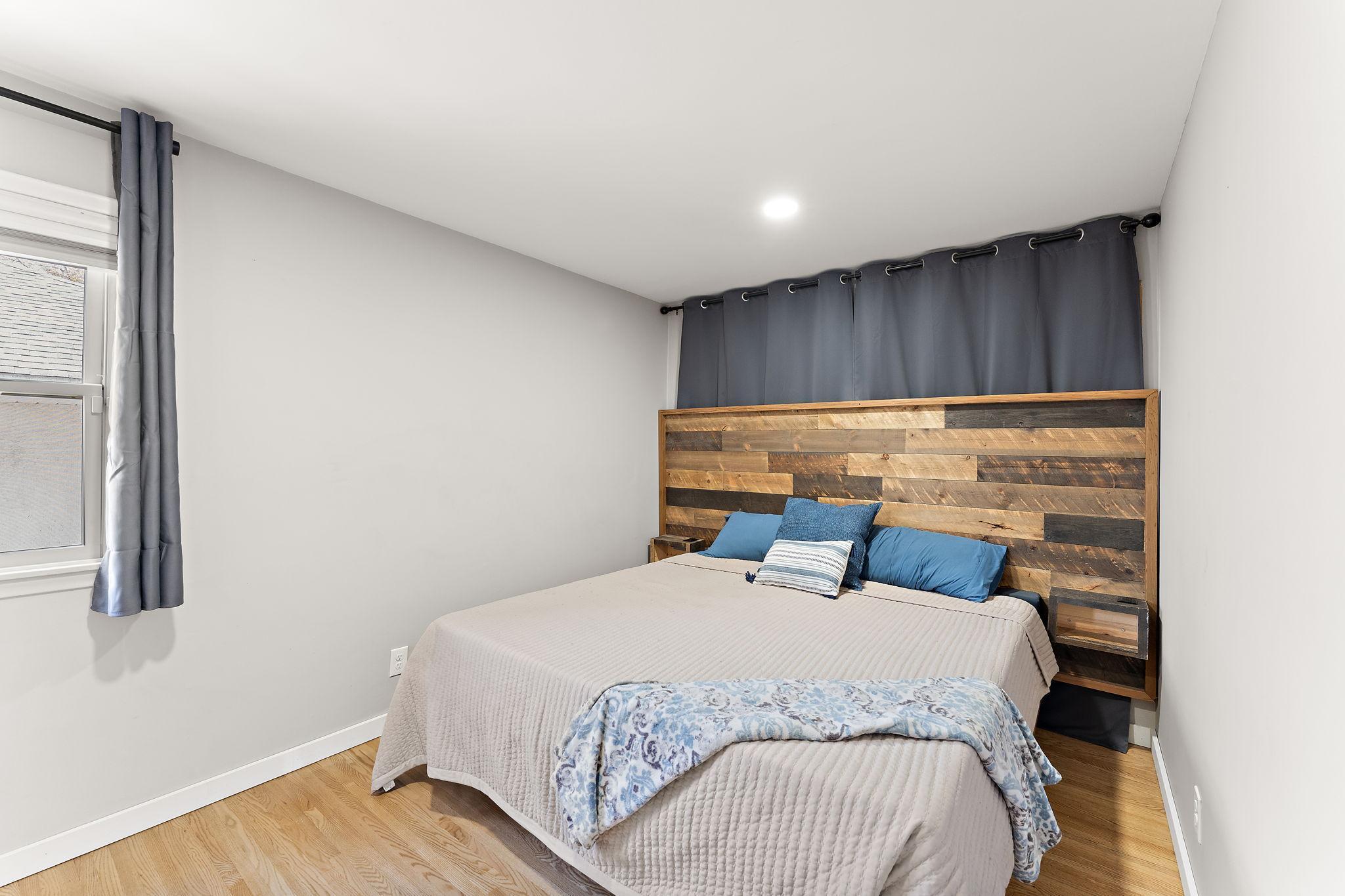 The main floor primary bedroom with king size bed has refinished hardwood floor and fresh paint.