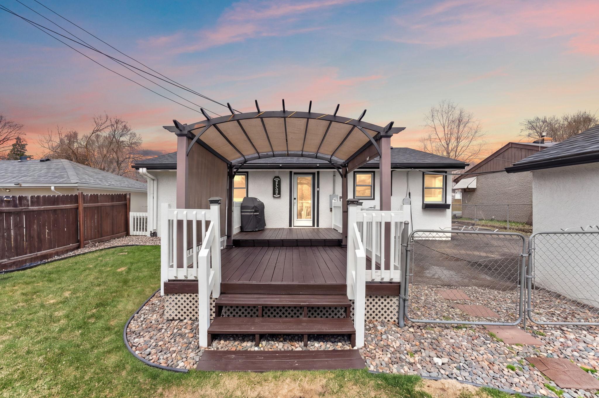 A twilight backyard view of the property featuring a pergola and deck which has been newly stained.