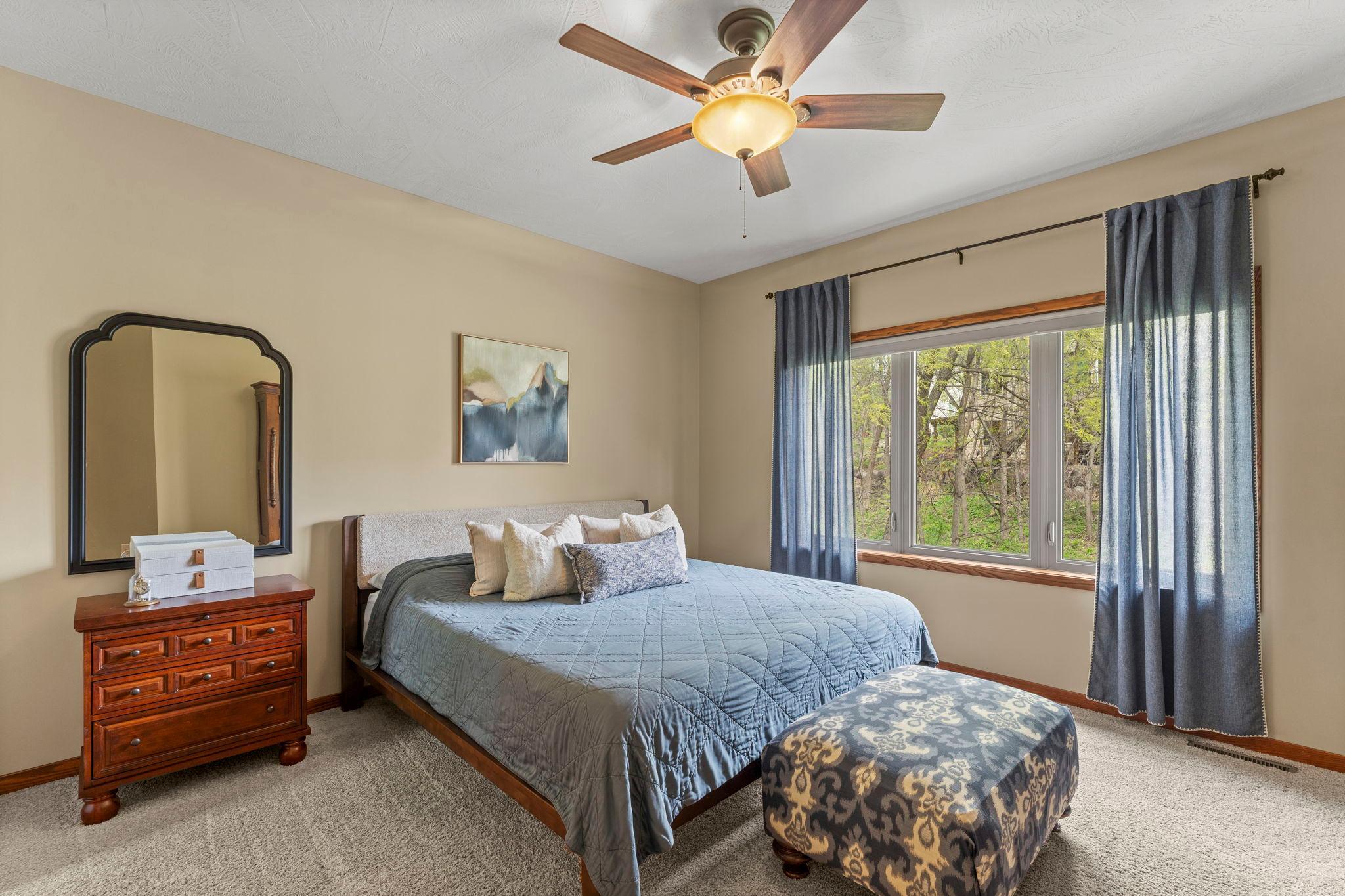 Main floor primary suite includes a ceiling fan and gorgeous views of the backyard