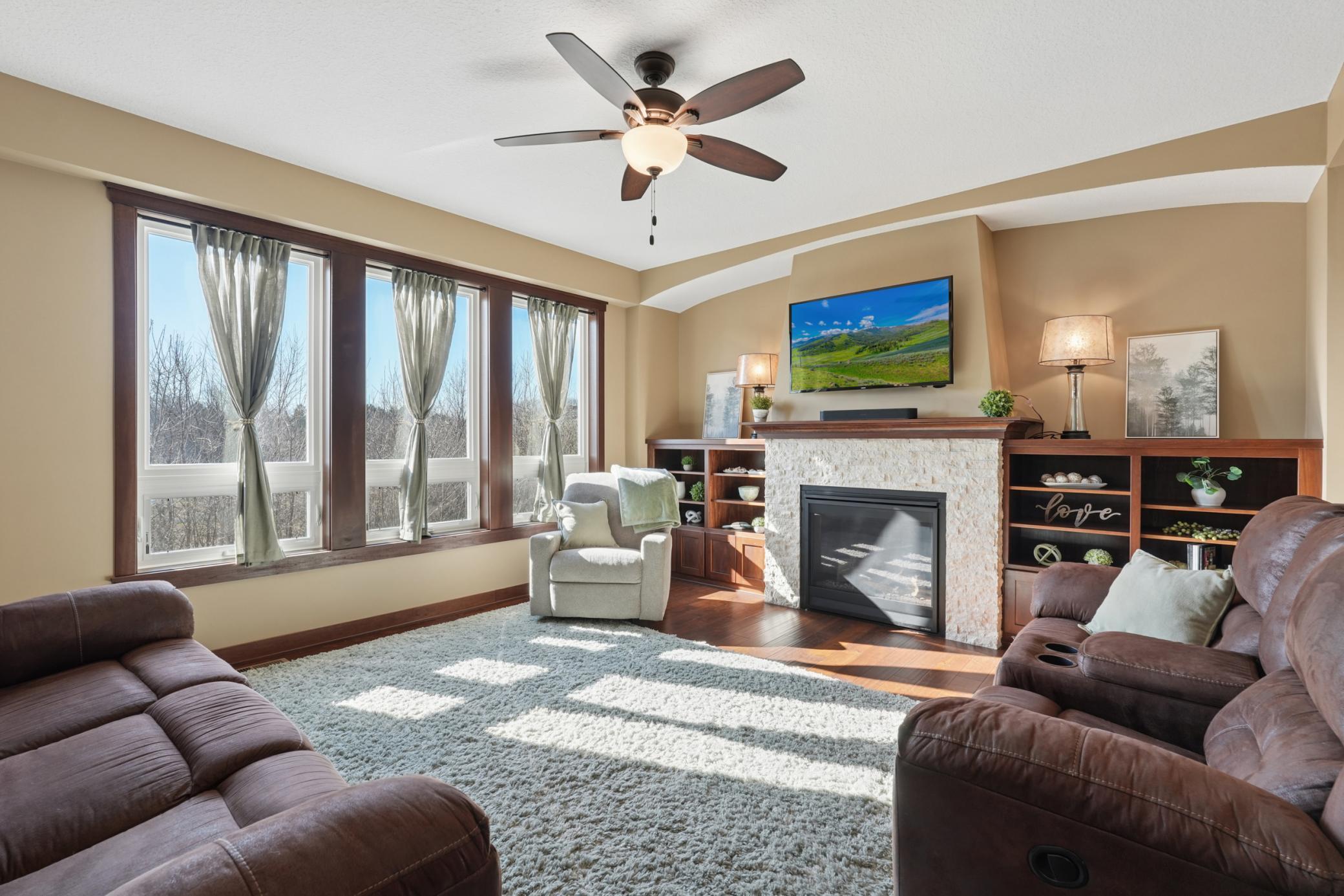 The heart of the home! This living room features a dramatic stone-front gas fireplace flanked by custom built-in bookcases, creating a warm and inviting gathering space for all seasons