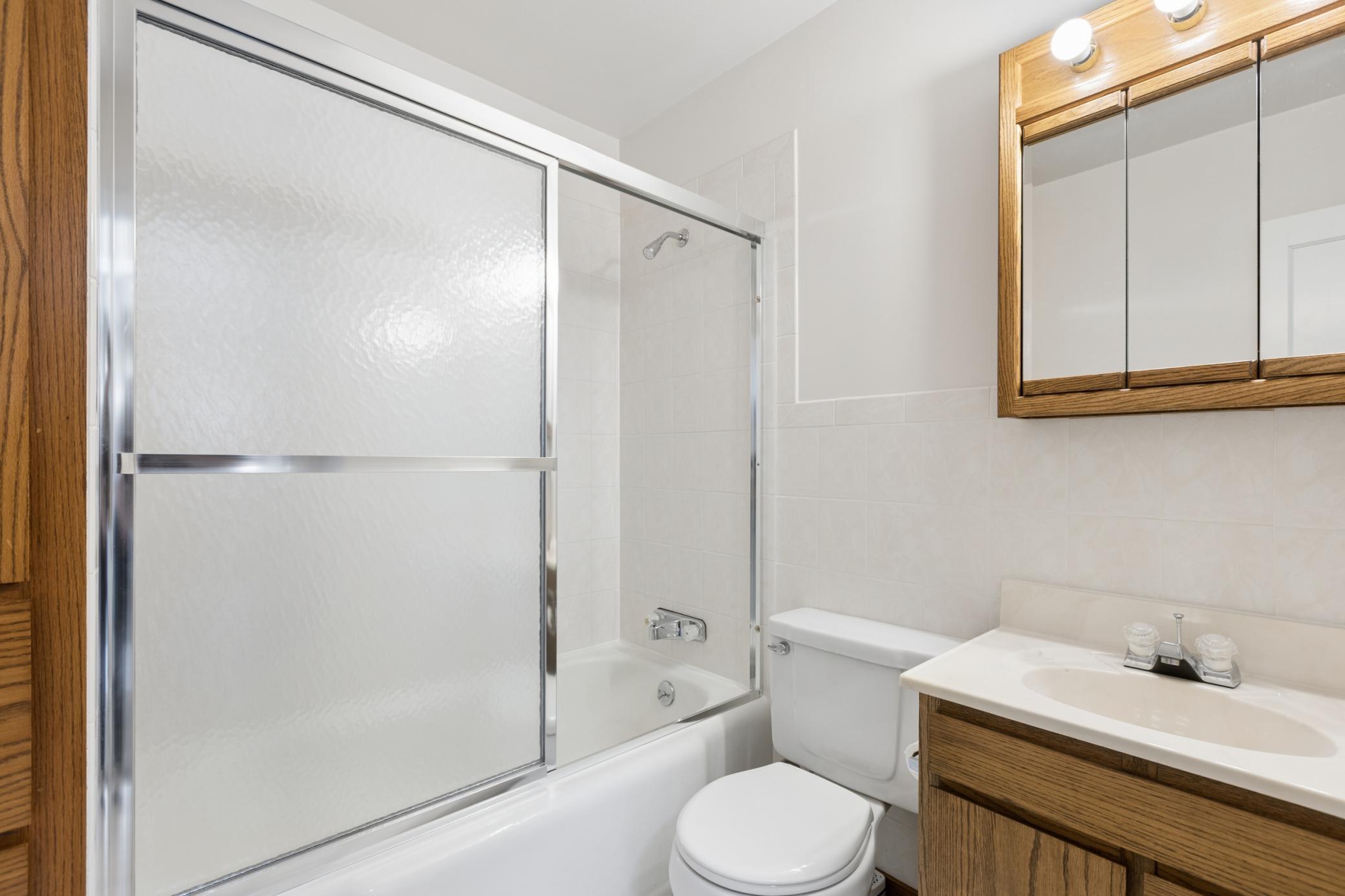 The full bathroom features a built-in linen cabinet and a tiled tub surround.