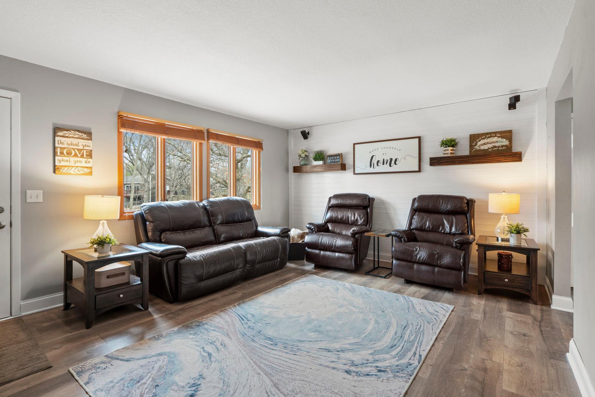 Cozy living room space offers shiplap accents, LVP flooring and large windows.