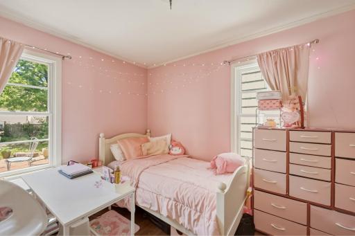 A sweet and sunny main floor bedroom with two windows, crown molding, and a peek of the backyard deck.