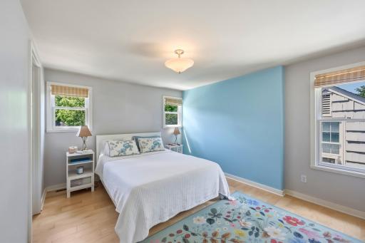 The upstairs primary suite offers new maple hardwood floors (2023), multiple windows, a walk-in closet, and room for a sitting area or home office.