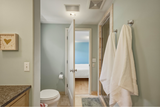 En suite bath with granite vanity, tiled shower, and direct access from the primary bedroom.