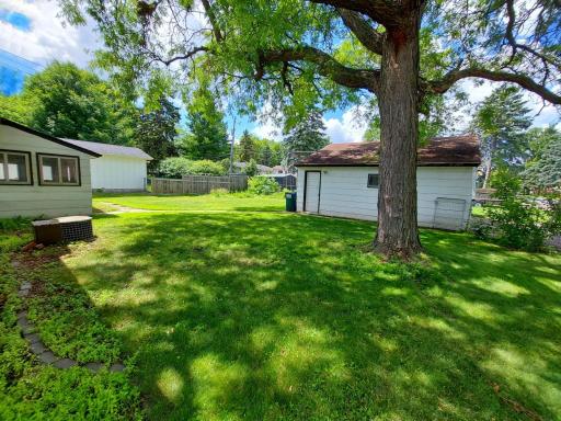 View from the side yard towards the backyard. photo left = 3 season porch. photo right 2 car garage with driveway to side street.