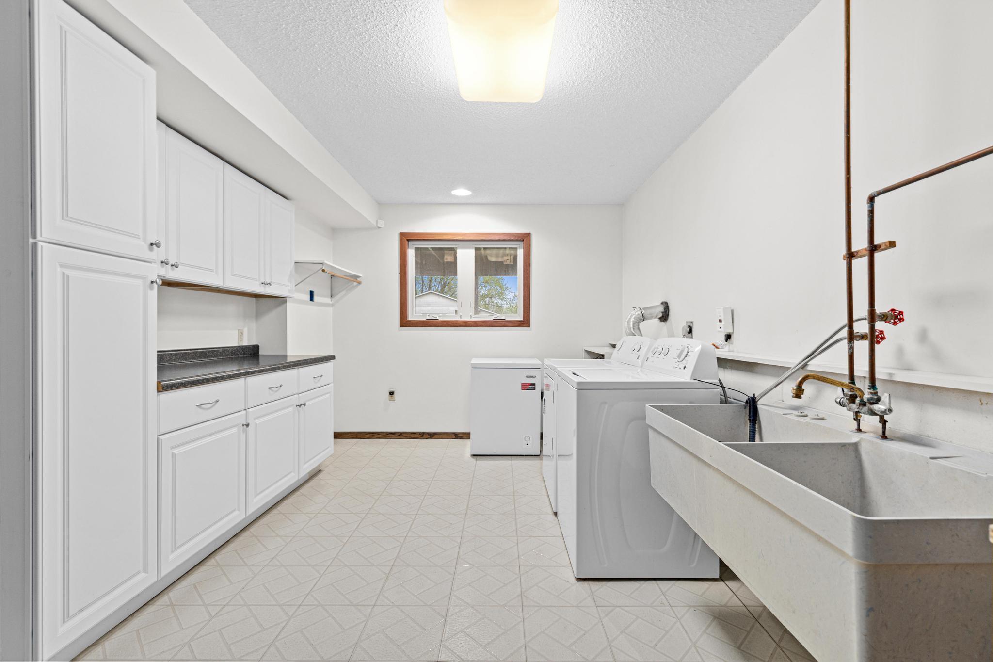 Enormous laundry room with a window, ample built-in storage, sink, and workspace.