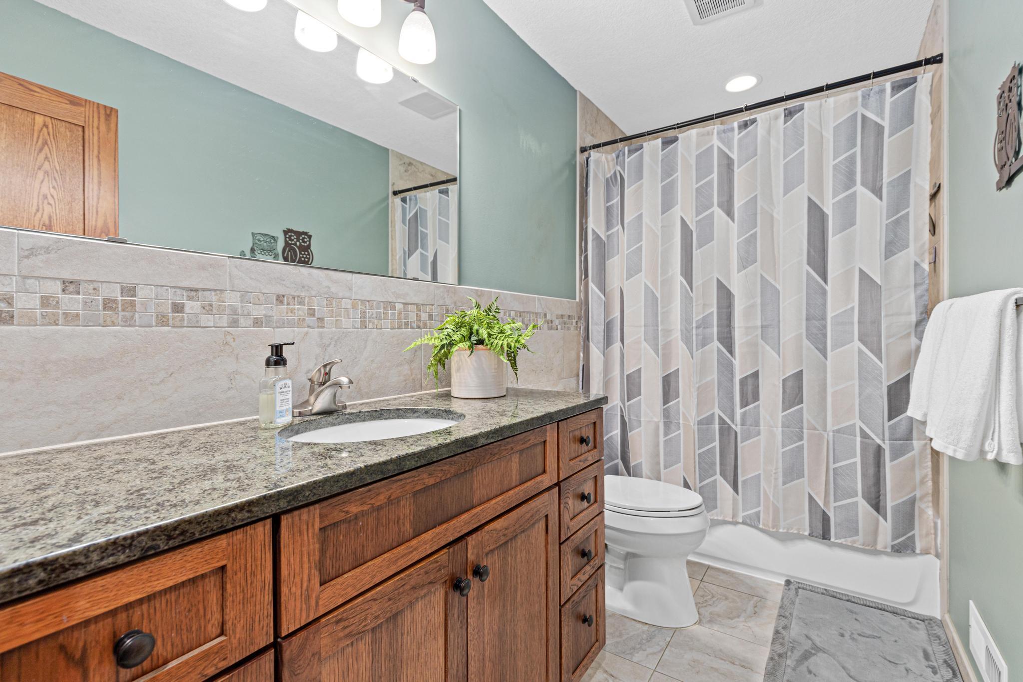 Updated upper full bath with granite vanity.