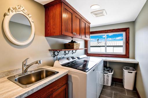 Convenient main-floor laundry room offers ample storage and easy access for everyday living. Appreciate the functionality of the space with a folding counter, cabinets and sink.