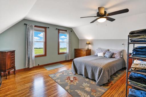 A cozy, sunlit bedroom featuring neutral tones, hardwood floors, closet space and generous square footage easily accommodating large furniture pieces.