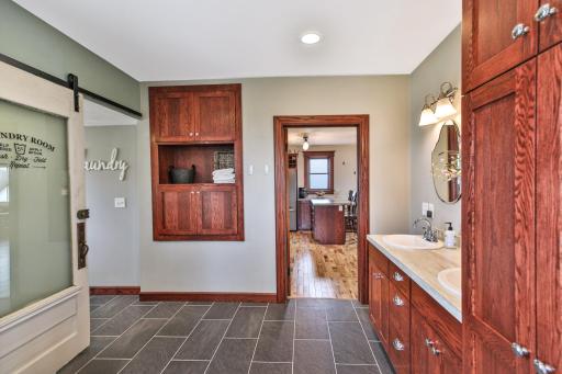 Main floor bathroom boasts an abundance of storage with a tall linen cabinet tower, built in cupboards and shelf. Laundry is attached with an antique styled door that perfectly finishes the space.