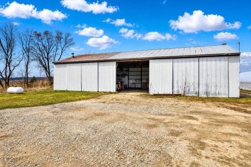 A spacious pole shed with metal roof and large open-face entry provides generous storage for equipment, tools, vehicles, or hobby space. It has electricity and a partial concrete floor.