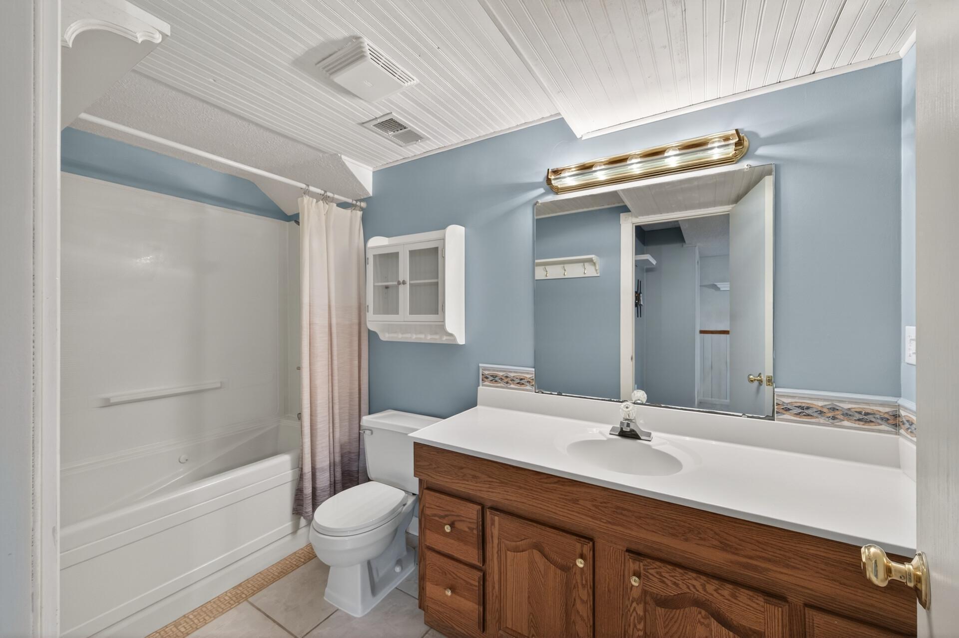The primary en-suite bathroom offers a jetted tub, a tiled floor, and extra countertop space.