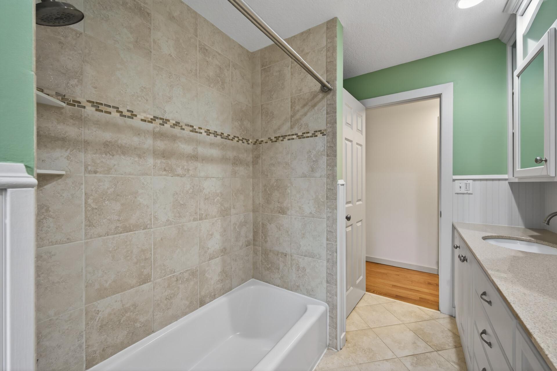 The upper level bathroom also features elegant tile flooring and a beautifully tiled shower creating a polished, spa-like atmosphere, enhanced by abundant natural light and high-quality finishes.