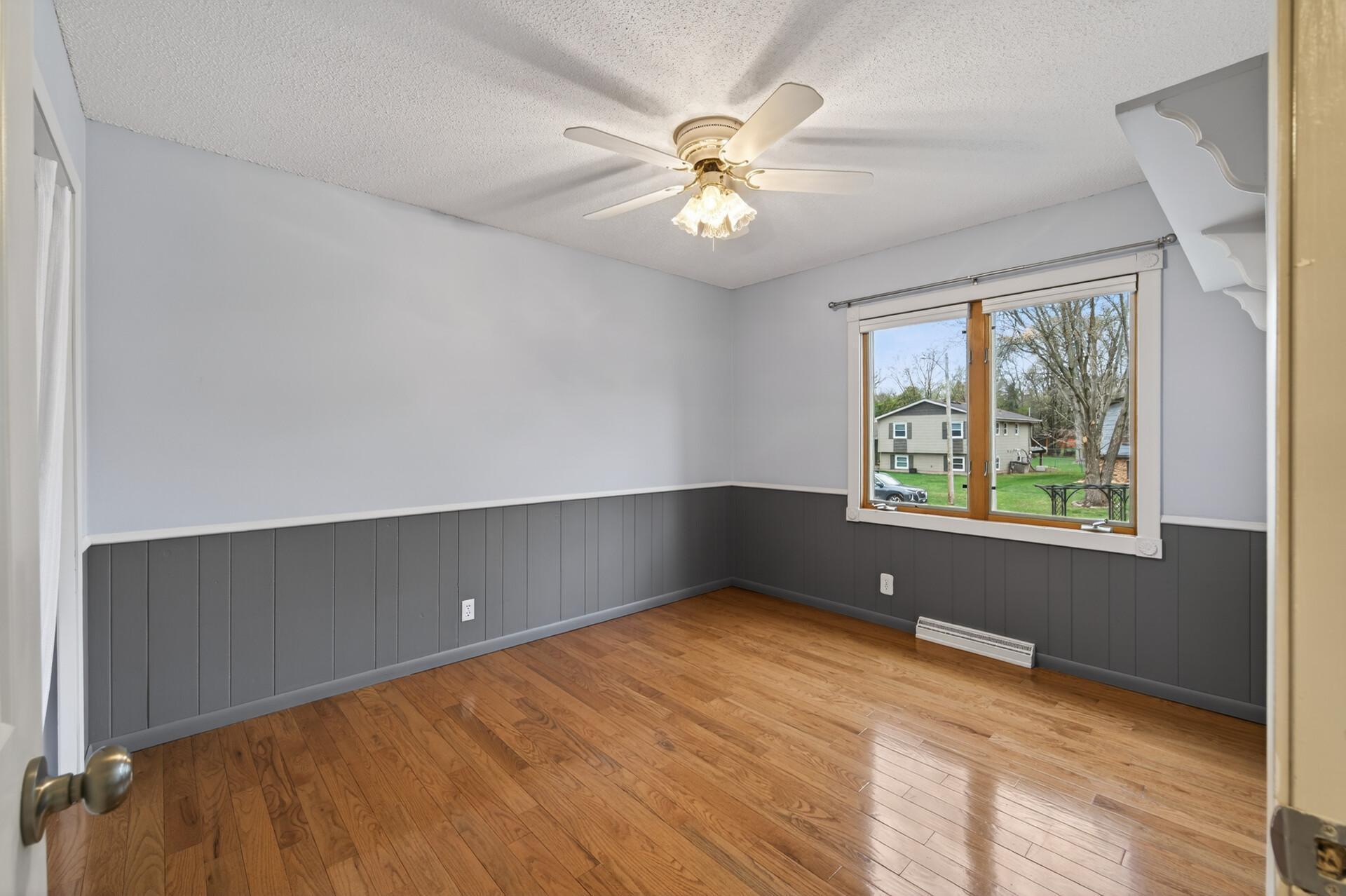 The second bedroom on the upper level features gorgeous hardwood flooring and a ceiling fan for added comfort.