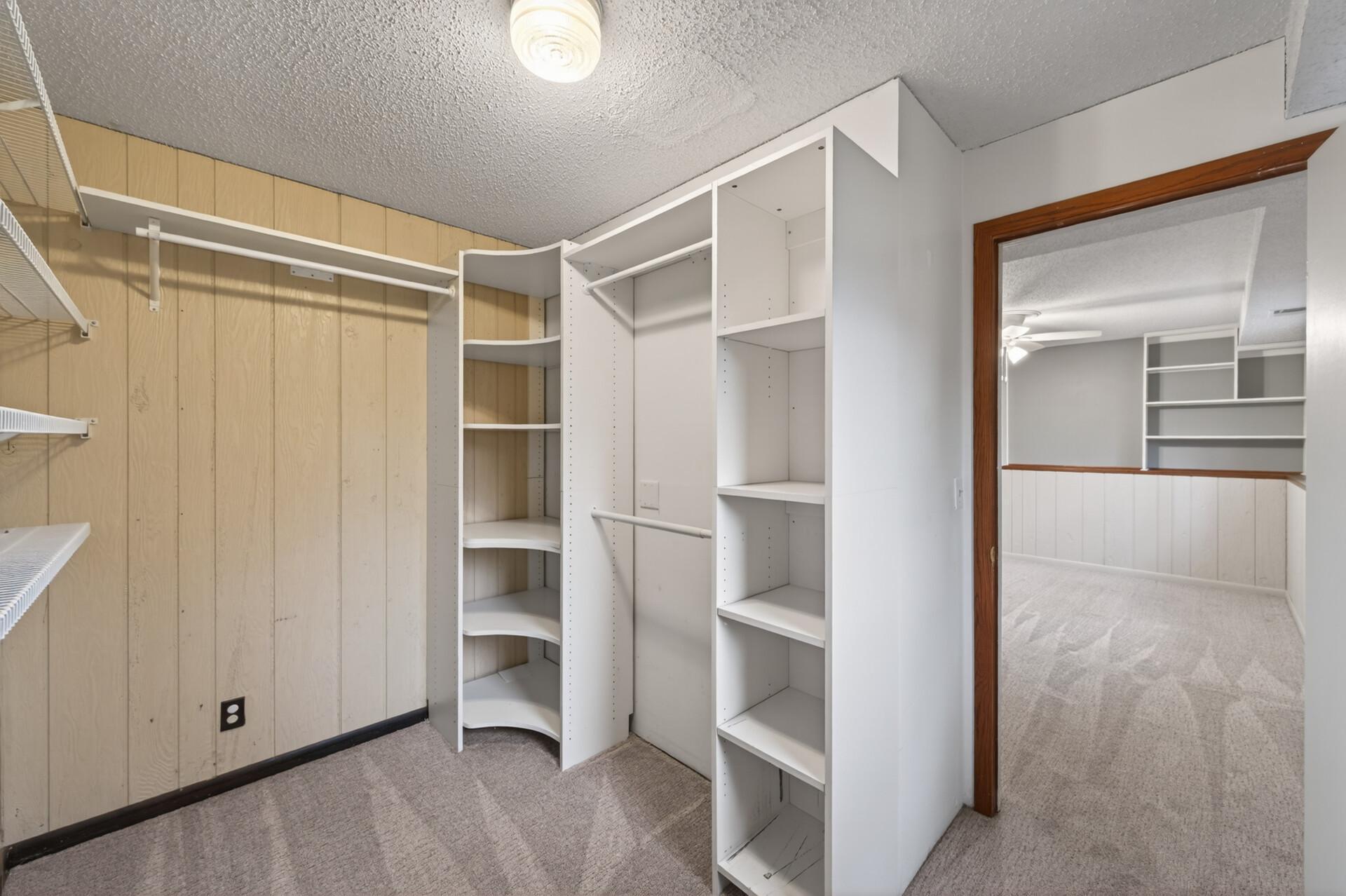 The beautifully organized primary suite walk-in closet showcases an abundance of custom shelving and built-in cubbies. The floor to ceiling storage offers dedicated space for shoes, handbags, folded sweaters, and accessories.