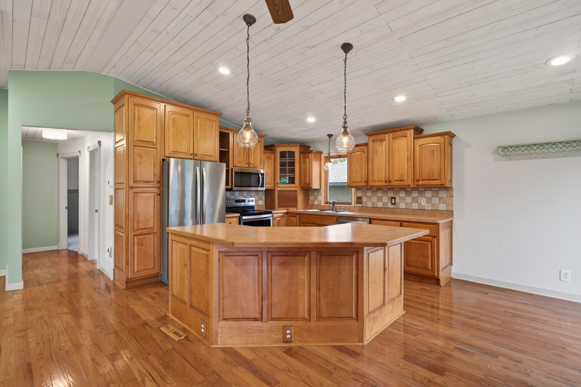 The kitchen includes a stylish tile backsplash and the island is perfect for additional seating, snack time, or setting up buffet meals.
