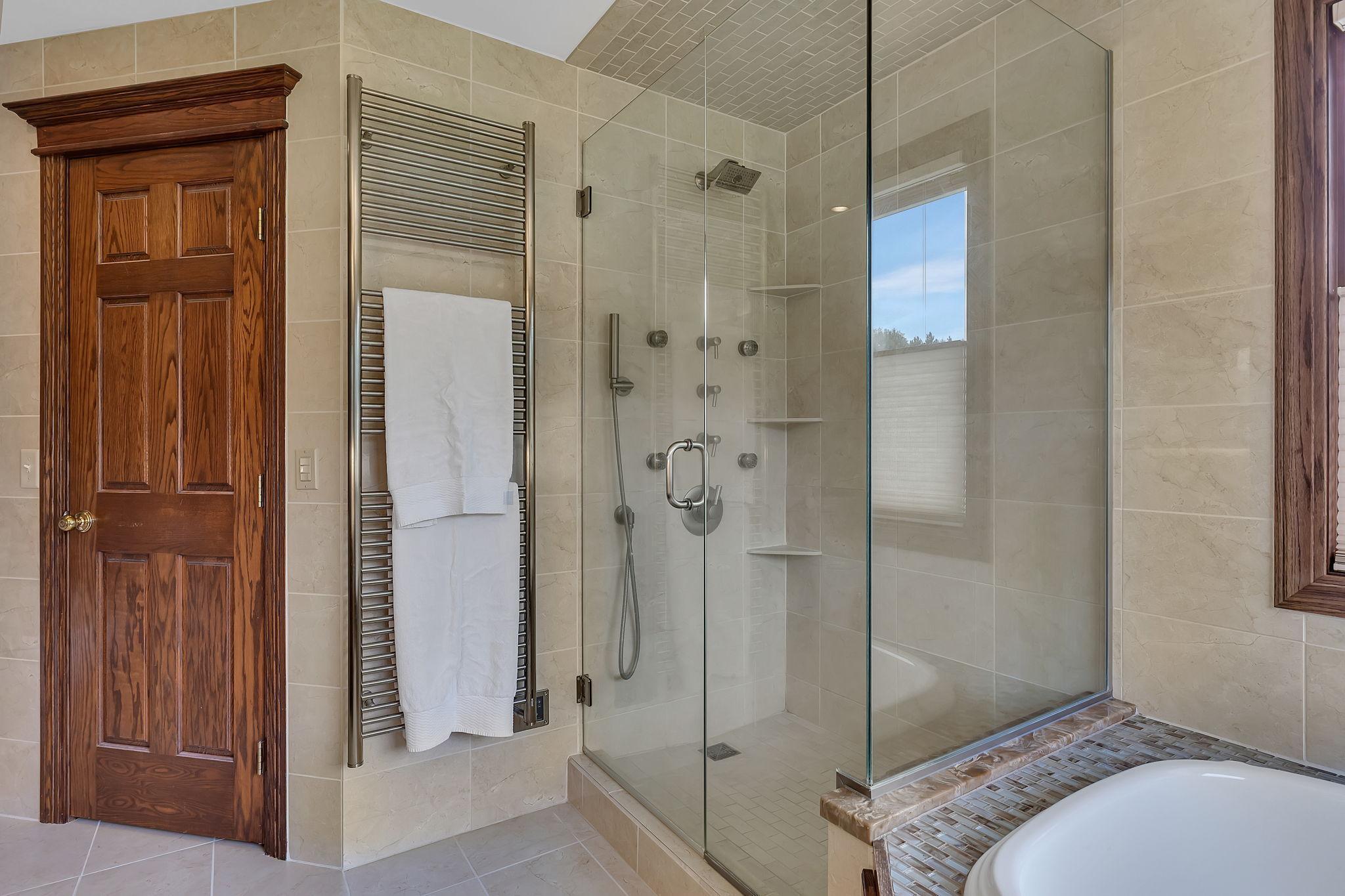 Onsuite bath glass doors, multipe shower heads and features and gorgous tile