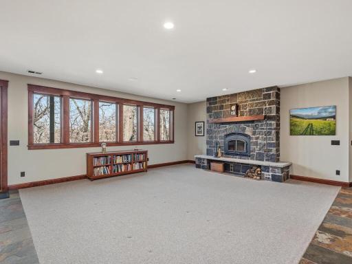 Lower Level Family Room features wall of windows and striking stone wood burning fireplace.