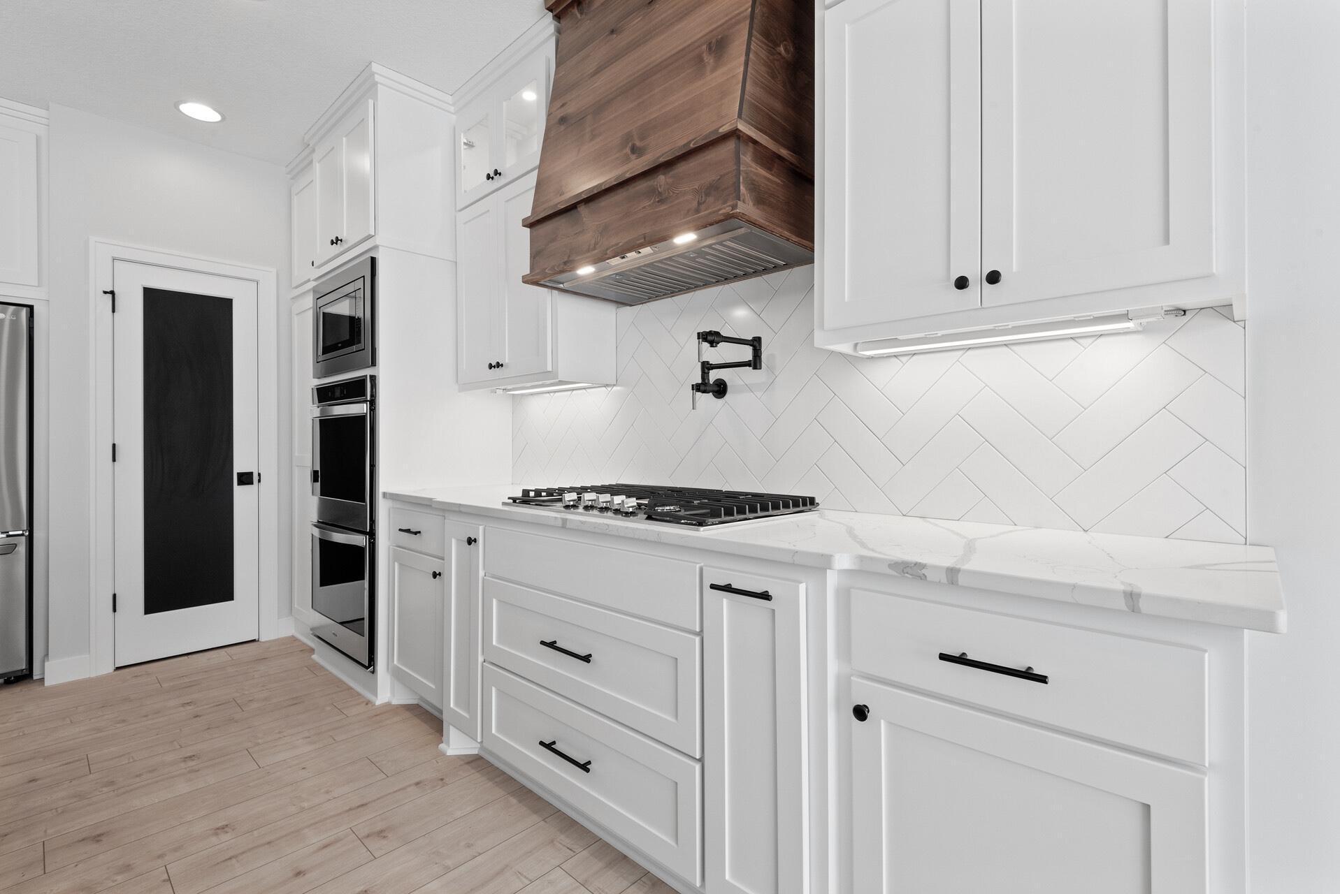 Cooking is more fun with a Pot Filler, Custom Vented Wood Hood, Tile Backsplash! Photo of previous home.
