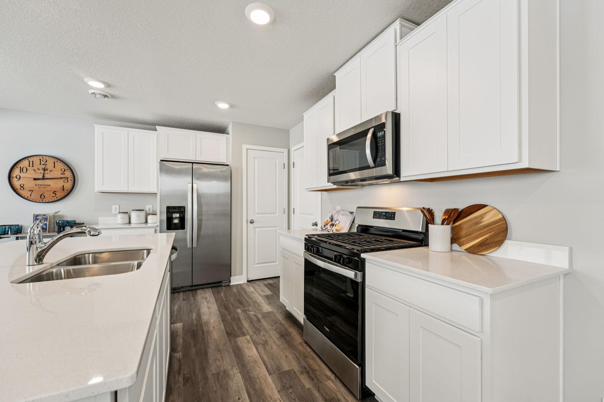 Thoughtfully designed kitchen with stainless appliance package including gas range, dishwasher and vented micro-hood. Photo of model home, color & options will vary.