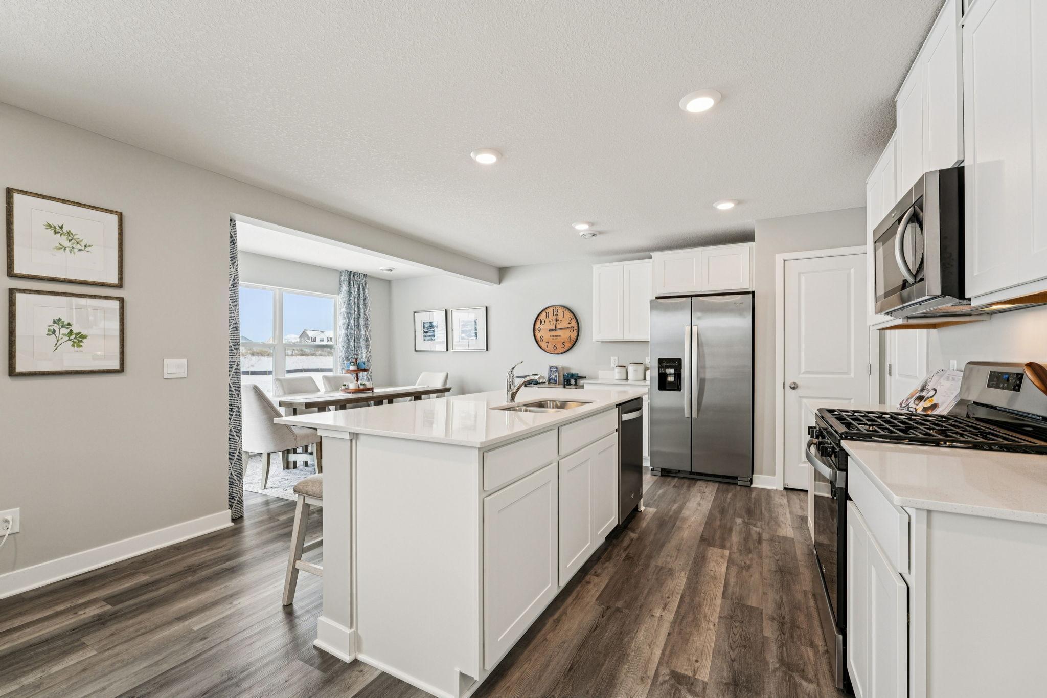 Thoughtfully designed kitchen with stainless appliance package including gas range, dishwasher and vented micro-hood. Photo of model home, color & options will vary.