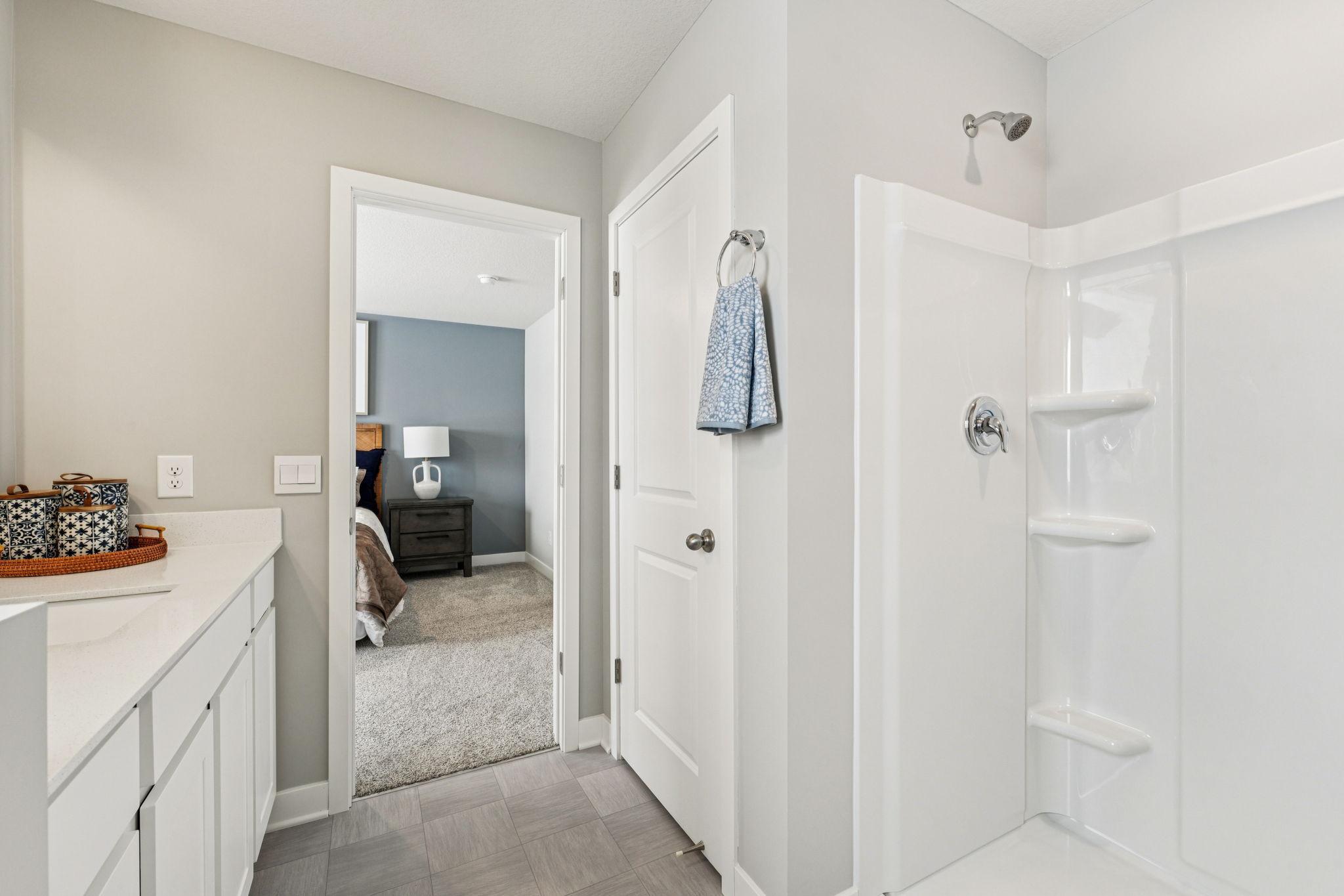 Private ensuite bathroom off primary with walk-in shower. Photo of model home, color & options will vary.