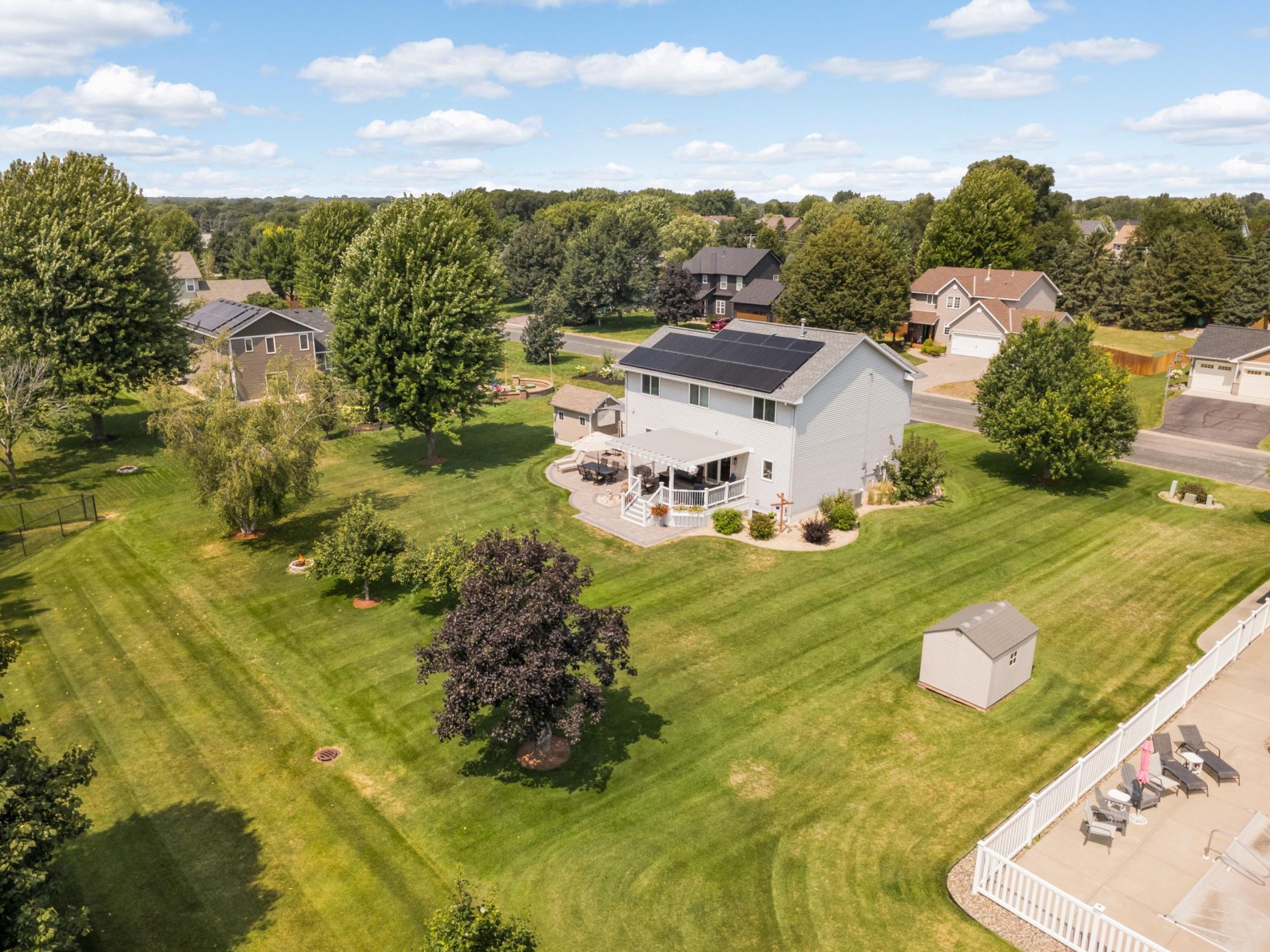Framed by a flat, tree-lined backyard with beautiful landscaping.