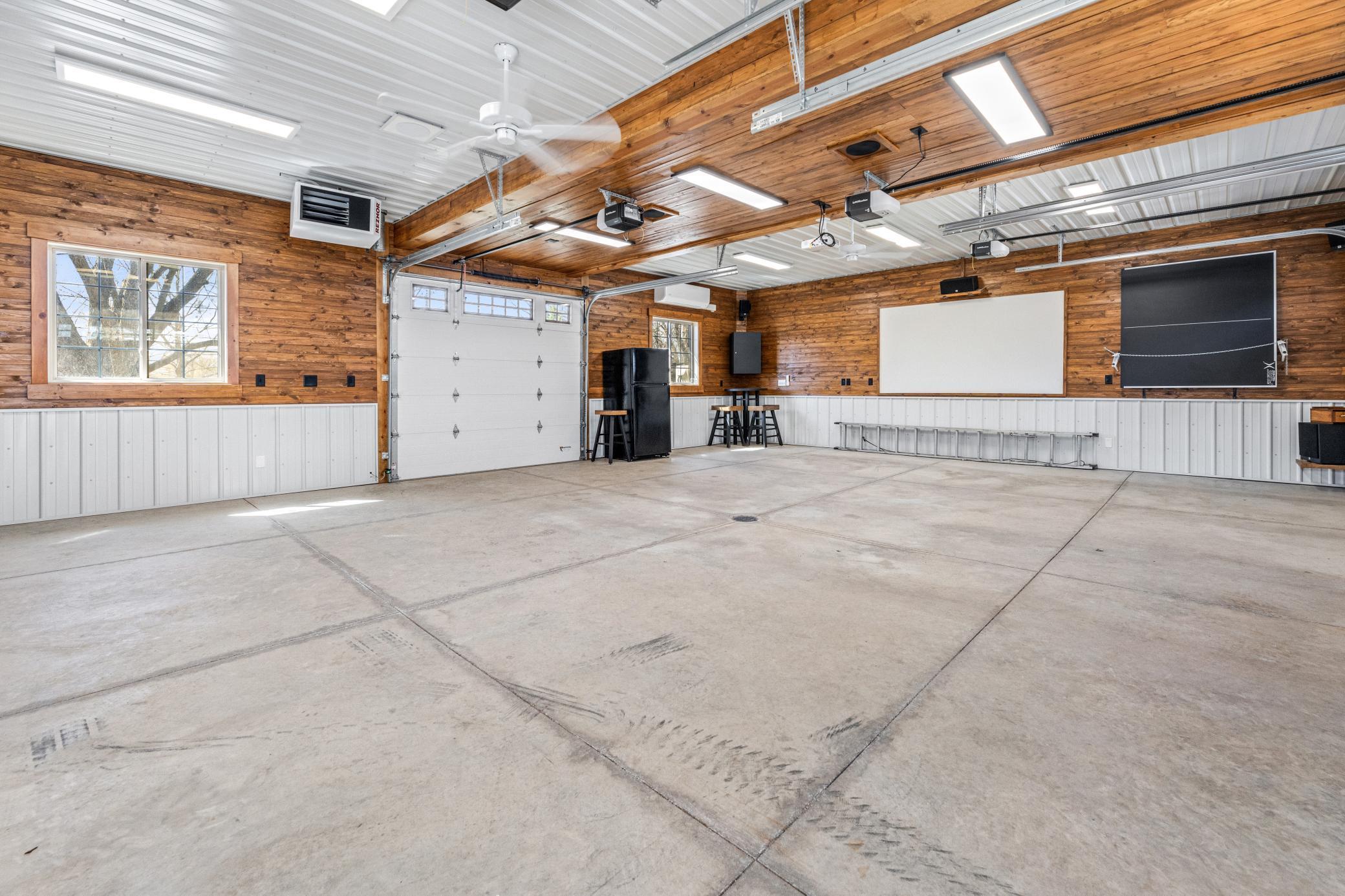 A large heated garage with air conditioning, surround sound, a projector screen, and a walk up attic