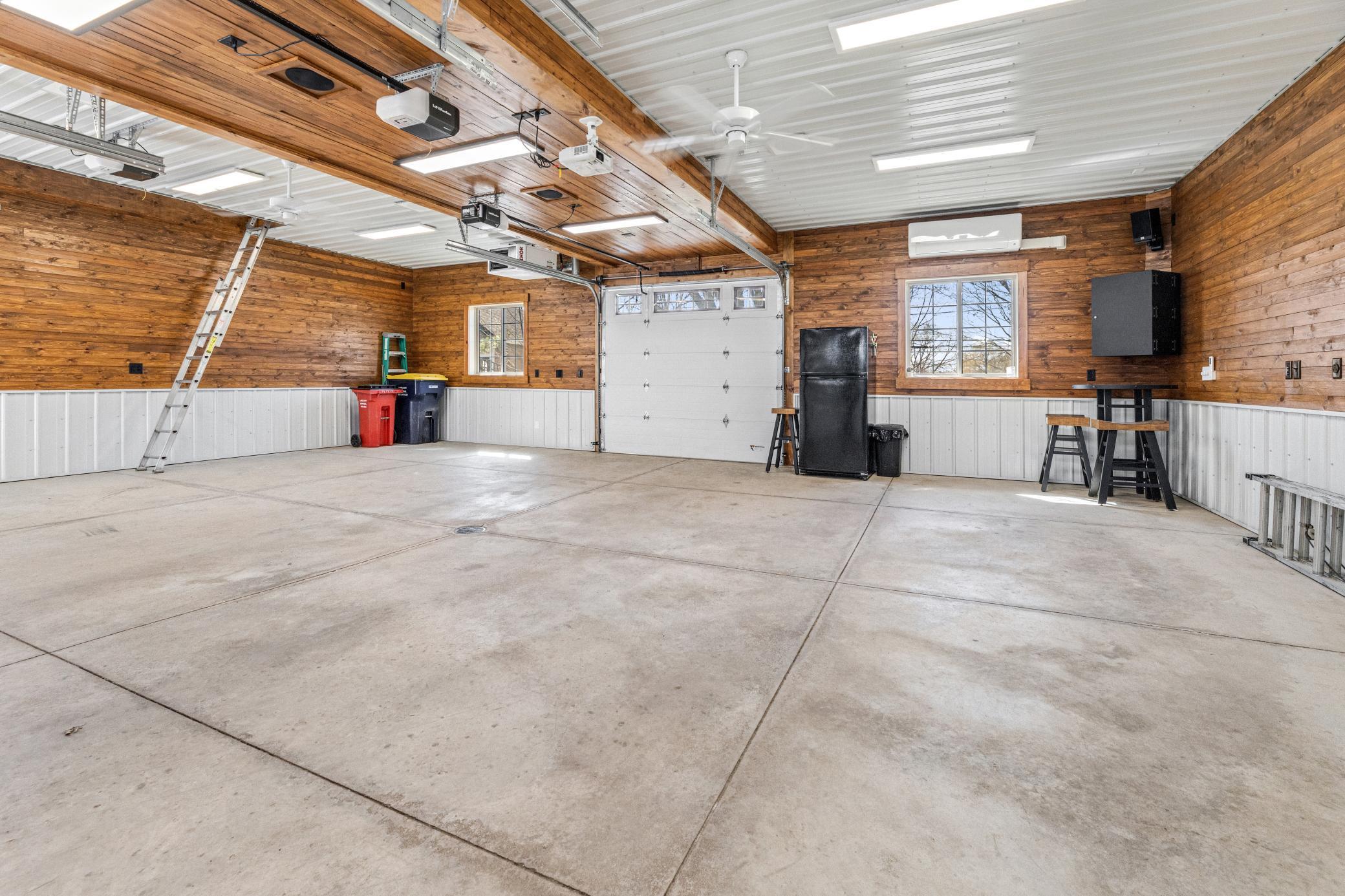 A large heated garage with air conditioning, surround sound, a projector screen, and a walk up attic