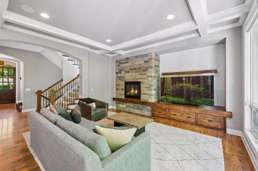 The living room features boxed ceiling, stone fireplance and natural lights