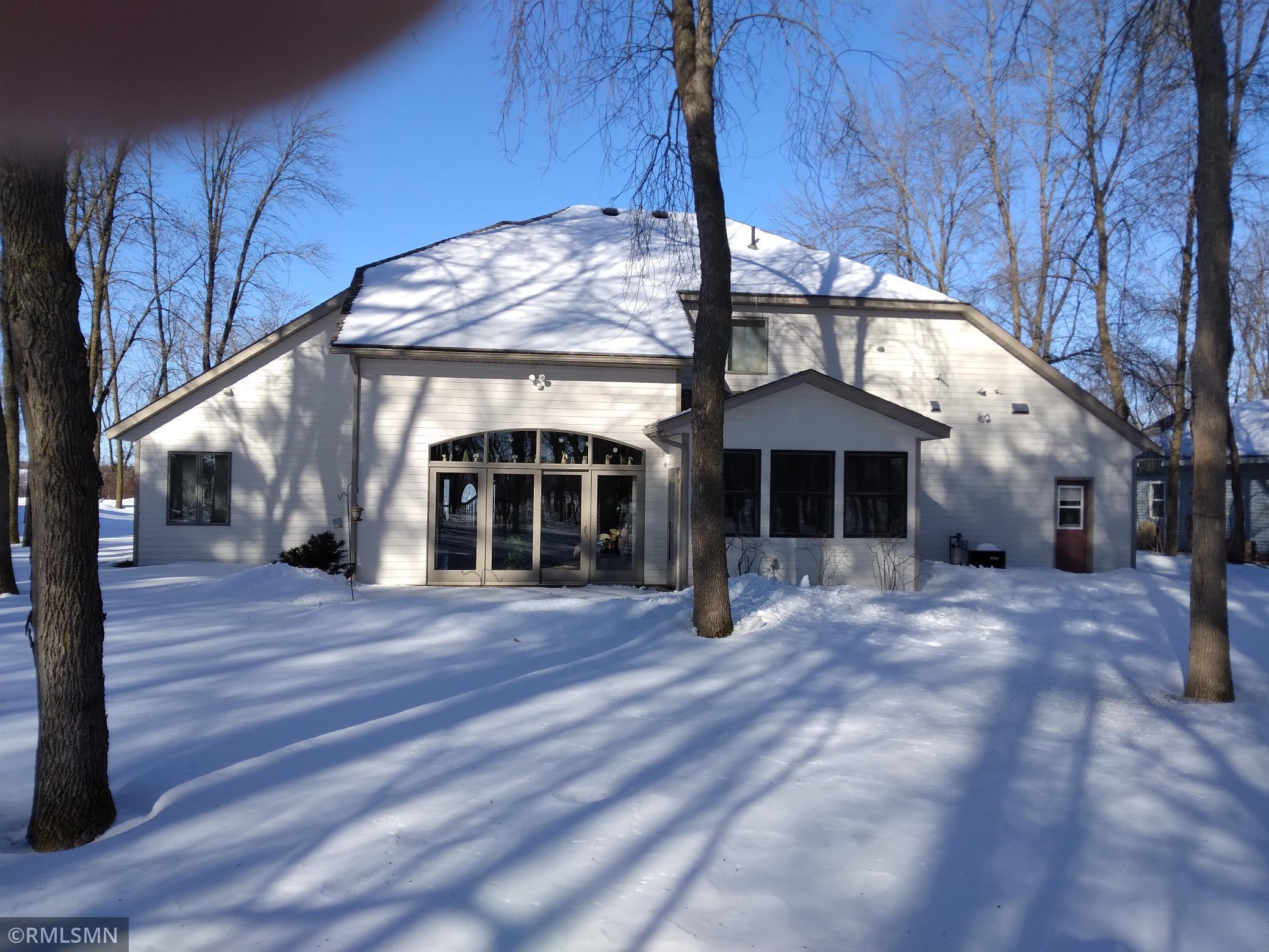 Back of home showing patio door in living room, 4 season porch,