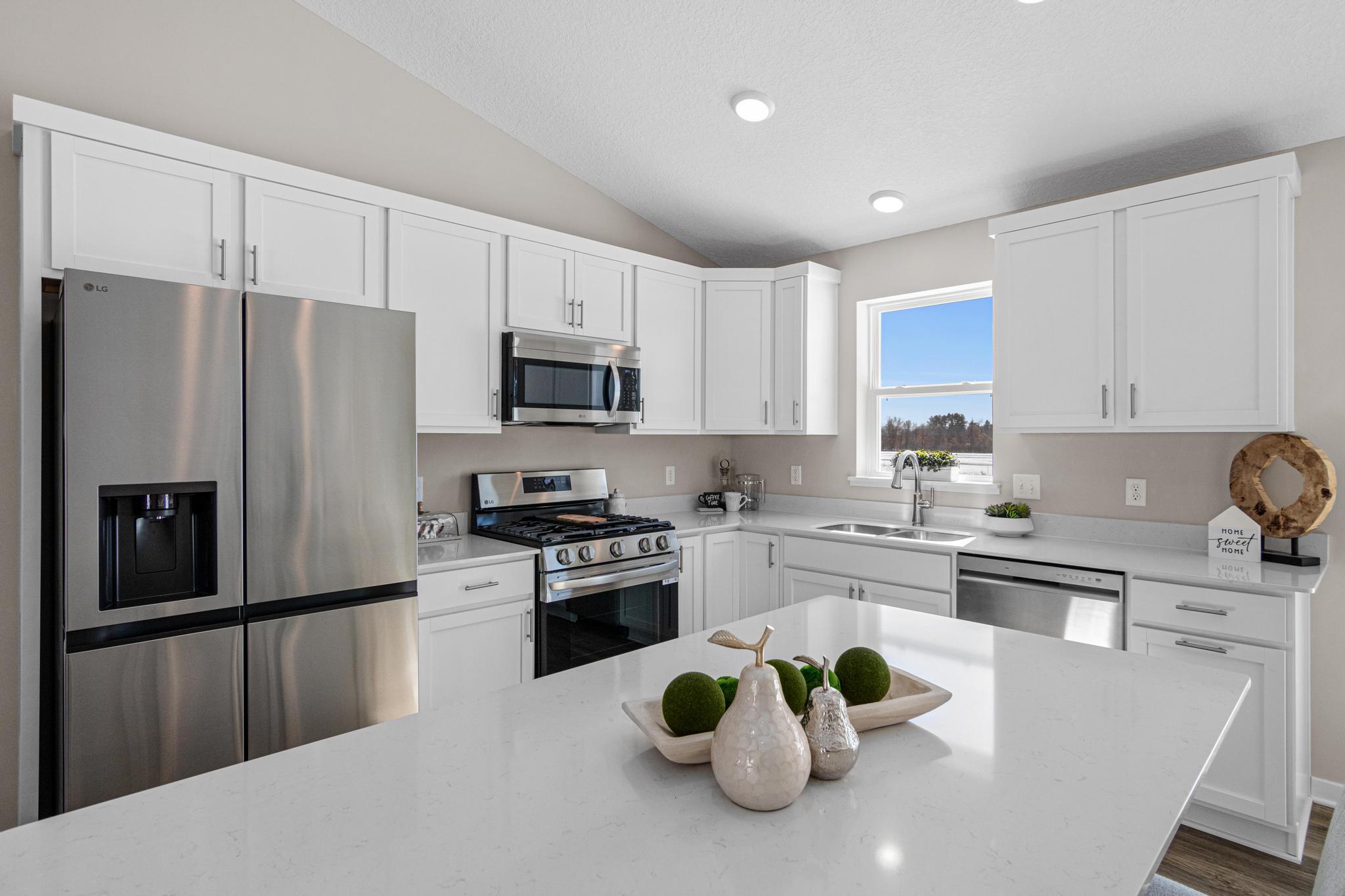 VIRTUALLY STAGED PHOTO OF A DIFFERENT HOME WITH SIMILAR PLAN & FINISHES. Kitchen features a window and center island. Photo may not depict actual plan, material, & finishes included in this home.