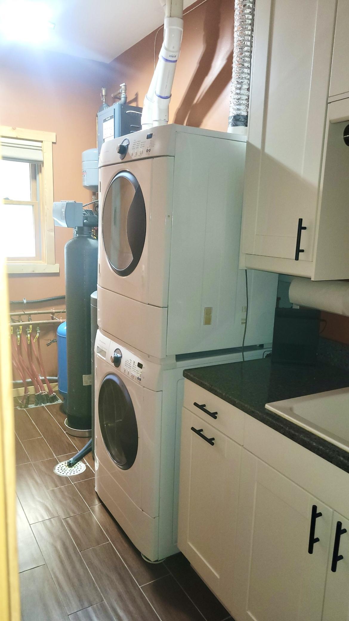Laundry room with utility sink and cabinets. Water softner