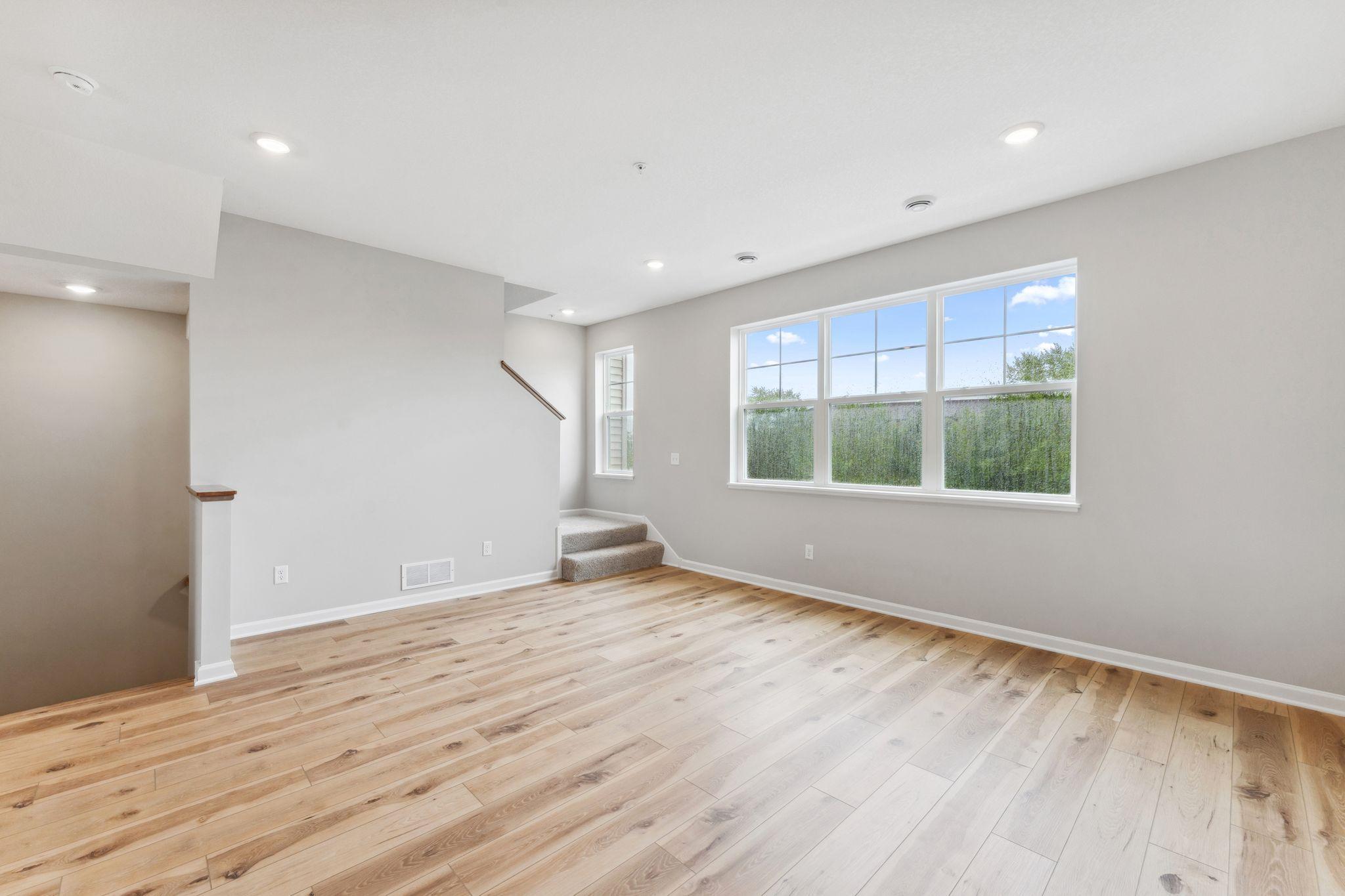 The spacious family room is filled with natural light. Similar home shown, color & finish can vary.