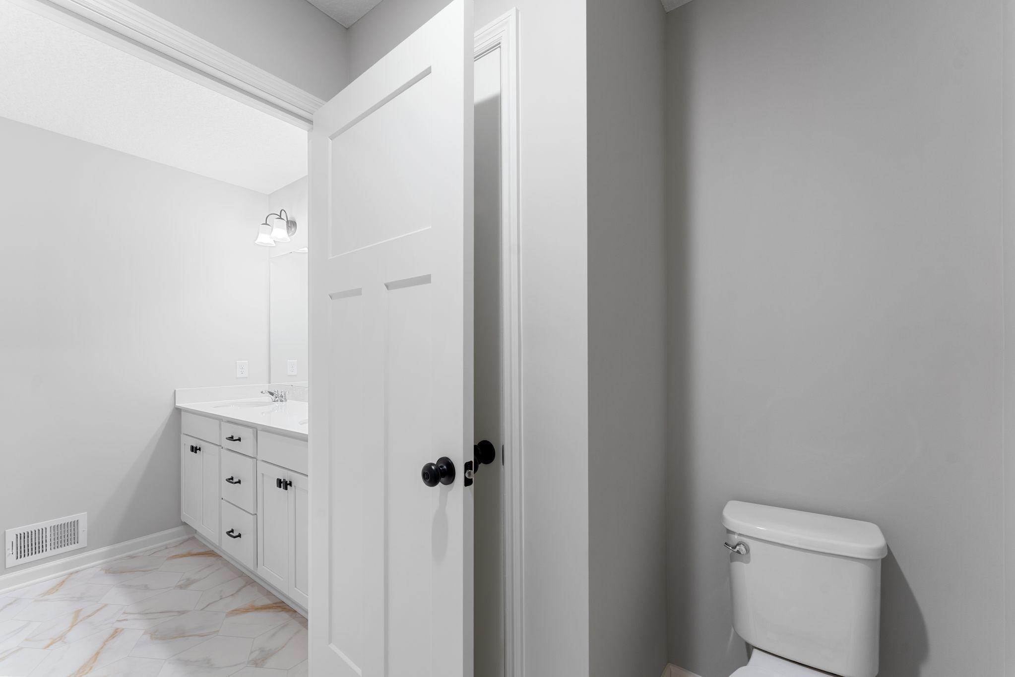 The main level bath features dual sinks, a large vanity for added storage. Similar home shown, color & finish can vary.