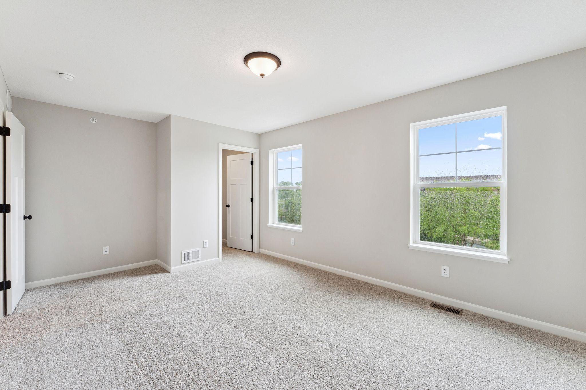 The secondary bedroom is equally impressive with walk-in closet, beautiful tree lined views, and natural light. Similar home shown, color & finish can vary.
