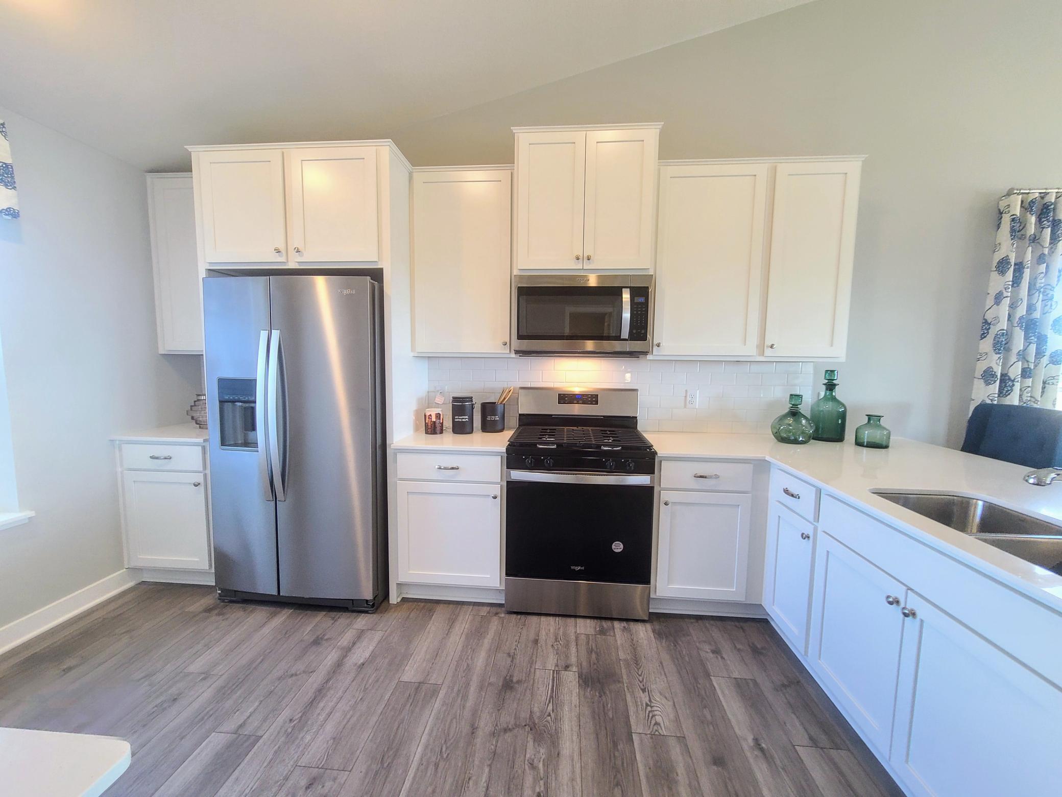 Kitchen shown with white cabinets, gas oven/range, microwave over cooktop, and quartz countertops. Photos is of model home. Colors and options may vary. Ask Sales Agent for details.