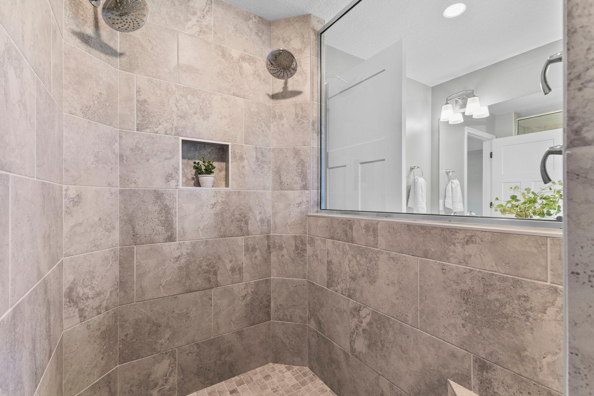 A stunning custom-tile shower with dual shower heads giving it a luxury feel!