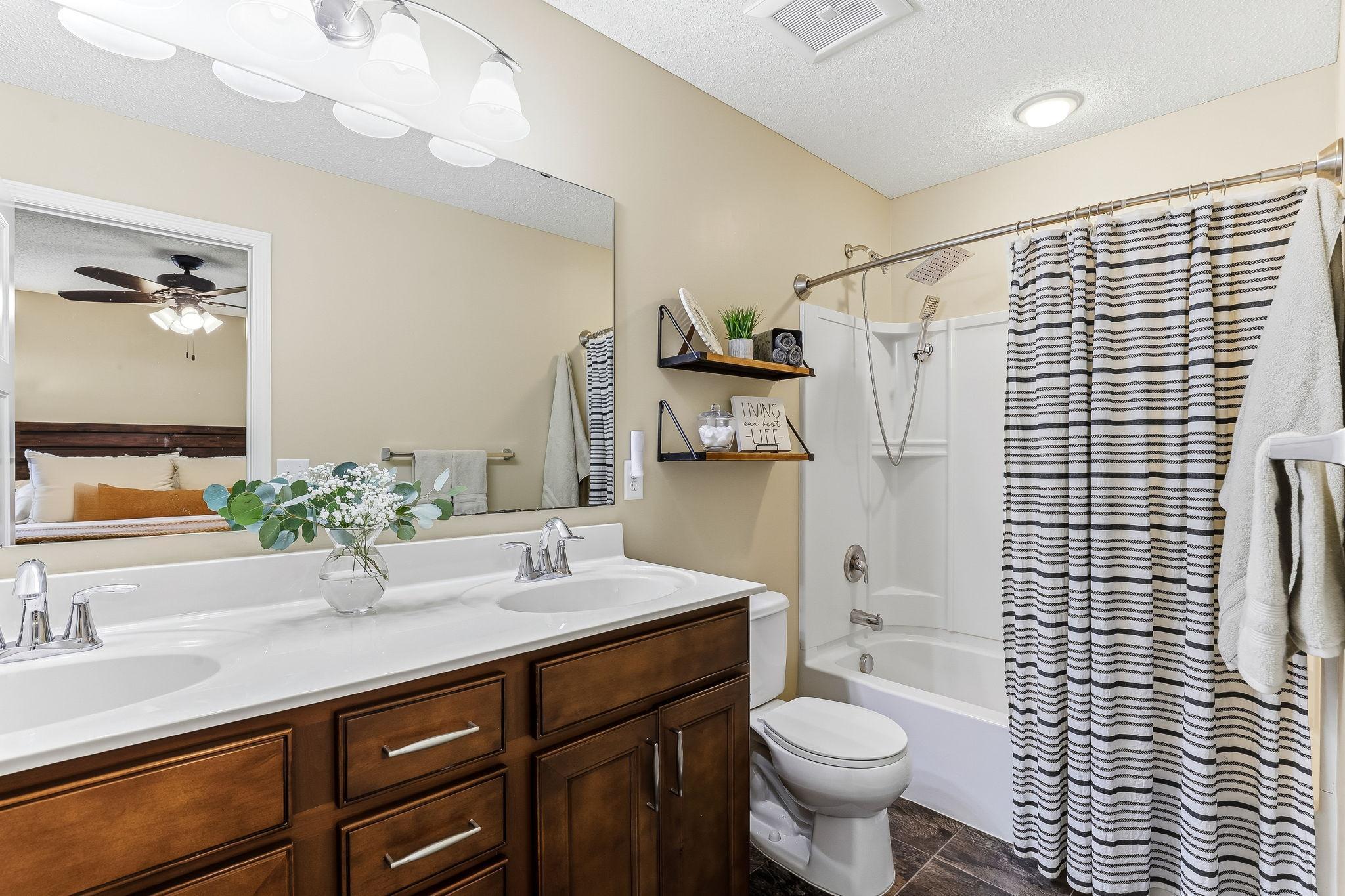 Primary bathroom featuring a tub/shower combination, dual vanities for added convenience, and modern lighting that enhances the bright, clean feel of the space.