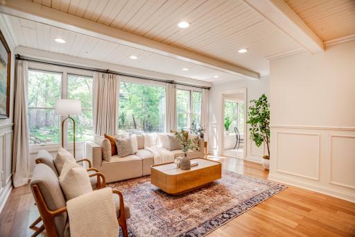 The spacious and bright family room features a beamed ceiling and a wall of windows overlooking the backyard.