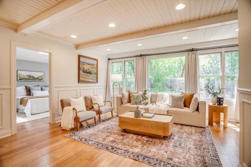 The spacious and bright family room features a beamed ceiling and a wall of windows overlooking the backyard.